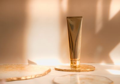 Cosmetic gold tube with on pastel background. Beauty product still life commercial ad photography. Cosmetic gold tube with on pastel background. Beauty product still life commercial ad photography.