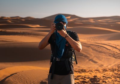 Photographer taking pictures in the sunny merzouga desert, morocco Photographer taking pictures in the sunny merzouga desert, morocco